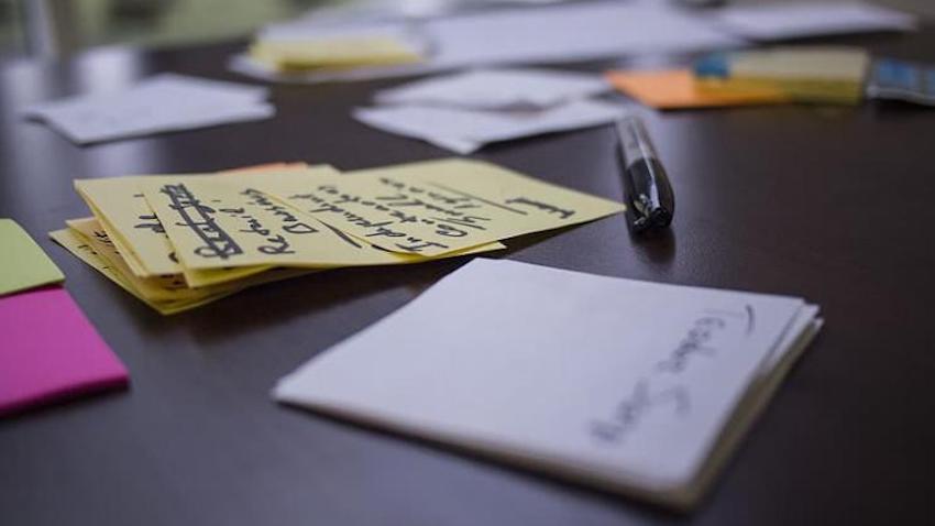 A table full of small sticky notes with writing and a black Sharpie marker.