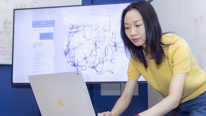 Sichen Jin leans over her laptop as she works
