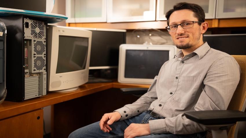 Zsolt Kira sitting in office chair surrounded by old computers