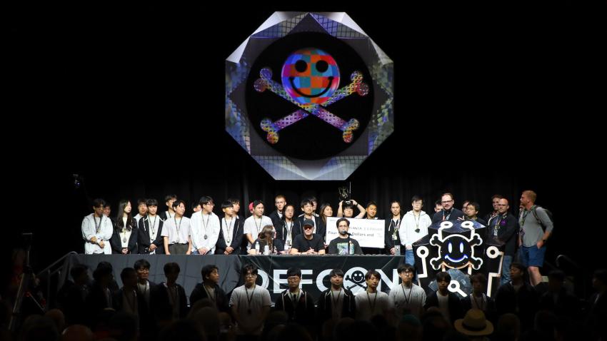 Team Atlanta stands on the dark DefCon stage during the convention's closing ceremony. 