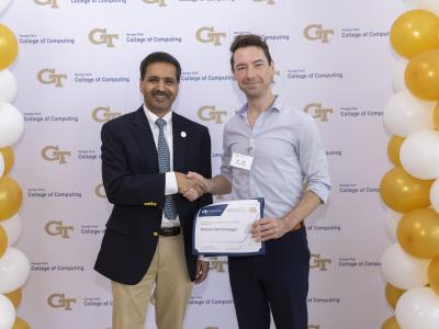 Two men shaking hands and holding a certificate.