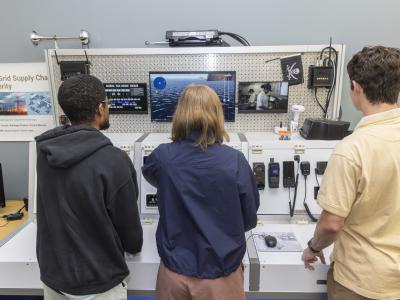 Three people working on a simulated ship in a lab