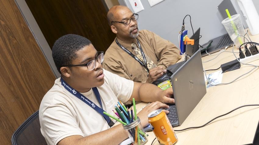 GT Computing's Sababu Barashango (top) monitors a student's progress during an interactive session that's part of the 2026 Georgia Tech Summer Institute.
